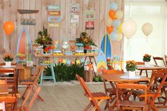 a party with balloons and surfboards on the wall, table set up for an event