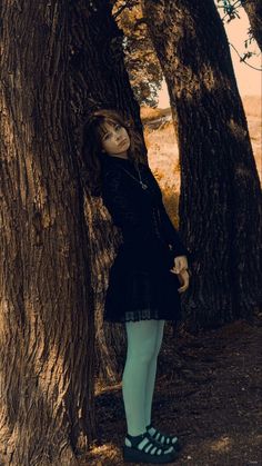 a woman standing next to a large tree