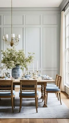 a dining room table with blue chairs and flowers in a vase on the centerpiece