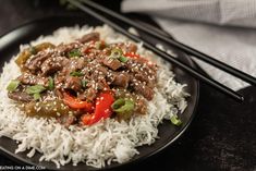 a black plate topped with rice and meat