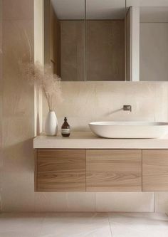 a bathroom with a sink, mirror and vase on the counter in front of it