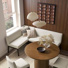 a living room filled with furniture and a round wooden table surrounded by white couches