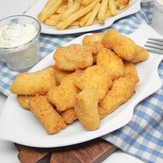 two plates filled with fish and fries next to some ketchup