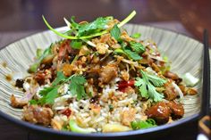 a white plate topped with rice and meat covered in cilantro, green onions and parsley