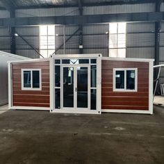 a small house made out of wood and metal in a building with two windows on each side