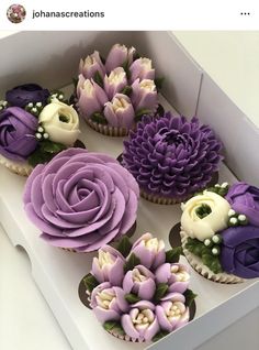 cupcakes decorated with purple and white flowers in a box