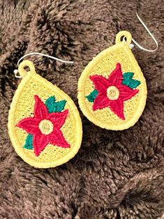 pair of earrings with red and green designs on brown furnishing, closeup