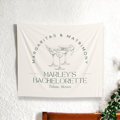 a white wall hanging on the side of a bed next to a potted plant