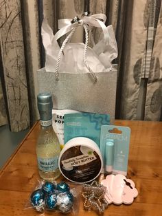 an assortment of personal care items sitting on a table next to a shopping bag and some candy