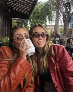 two beautiful young women sitting next to each other holding coffee mugs in their hands