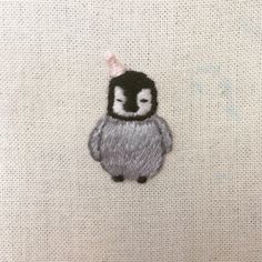 an embroidered animal with a pink bow on it's head sitting on a piece of fabric