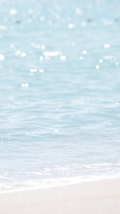 a person standing on the beach with a surfboard in their hand and looking at the water