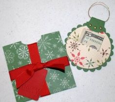 an ornament with a red bow on it next to a green gift box