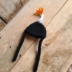 a crocheted black hat with a red and yellow pom - pom