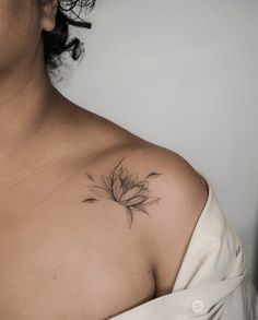 a woman's shoulder with a flower tattoo on the left side of her chest