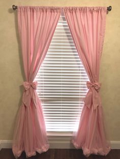 the window is decorated with pink curtains and bowknots, along with a wooden floor