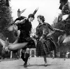 two people dressed in old fashioned clothing with birds flying around them and one man is holding the woman's hand