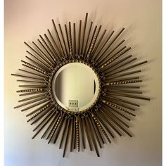 a sunburst shaped mirror mounted on the wall next to a white wall in a room