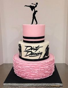 a pink and black cake with a dancing figure on it's top tiers