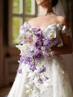 a bride holding a bouquet of purple and white flowers