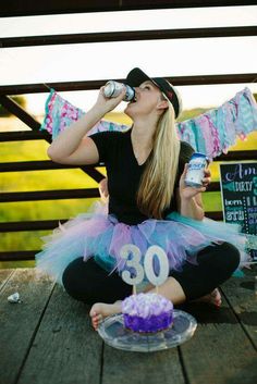 a woman sitting on the ground drinking from a can and wearing a birthday cake outfit