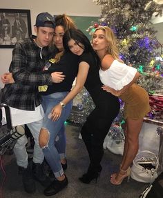 four people posing in front of a christmas tree