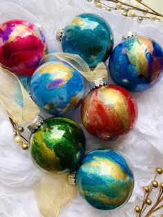 six ornaments with different colors and designs on them sitting on a lace covered table cloth