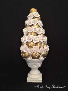 a white vase with gold and white flowers on it's sides, sitting against a black background