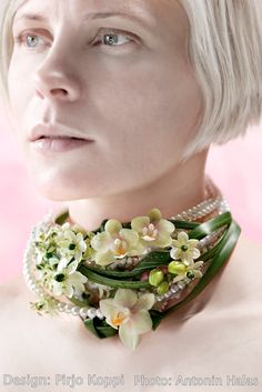 a woman with short white hair wearing a necklace and flowers on it's neck