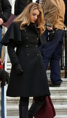 a woman in black coat and boots standing on steps