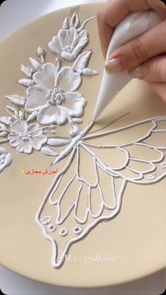 a person is using a marker to decorate a plate with flowers and butterflies on it