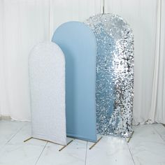 two large silver and white decorative objects sitting next to each other on a tile floor