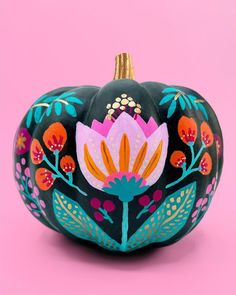 a painted pumpkin sitting on top of a pink surface