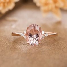 an oval pink diamond ring with three diamonds around it