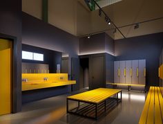 a yellow bench sitting in the middle of a room with lockers on both sides