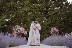 a bride and groom standing in front of lavender bushes