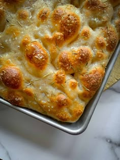 a casserole dish with meatballs and cheese in it on a marble surface