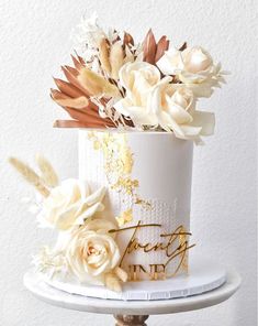 a white cake with gold lettering and flowers on top