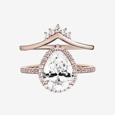 a rose gold ring with a pear shaped diamond on top and two rows of diamonds around the band