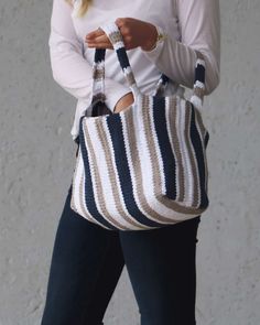 a woman is holding a striped purse