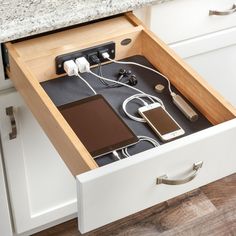 an open drawer in a kitchen with electronics and charging devices inside the drawers on each side