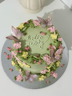 there is a green cake decorated with flowers and butterflies