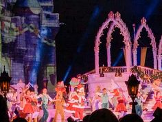 a group of people standing on top of a stage in front of a castle at night