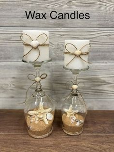 two candles are sitting in glass vases with seashells and starfish on them