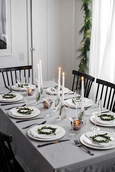 the table is set with white plates and silverware for christmas dinner guests to enjoy