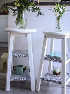 two white stools with flowers in vases on them