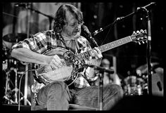 a man sitting in front of a microphone playing a guitar