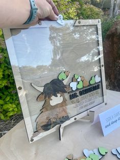 a person holding up a sign that has been cut out and placed on a table