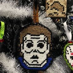 cross stitch ornament hanging from a christmas tree with other ornaments in the background