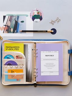 an open travel book on a table next to a pen, scissors and other items